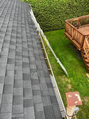 Before cleaning in La Prairie: compact debris blocking the gutter and downspout