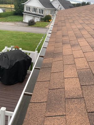 Before cleaning: residential gutter clogged with wet leaves and helicopter seeds in Longueuil